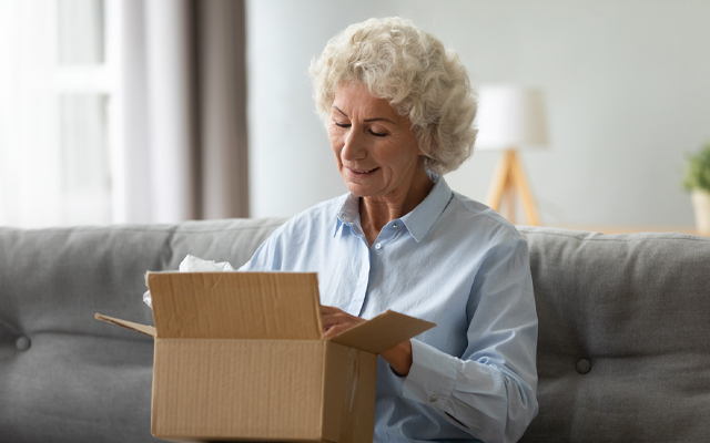 Older woman opening a box of medicines shipped to her home