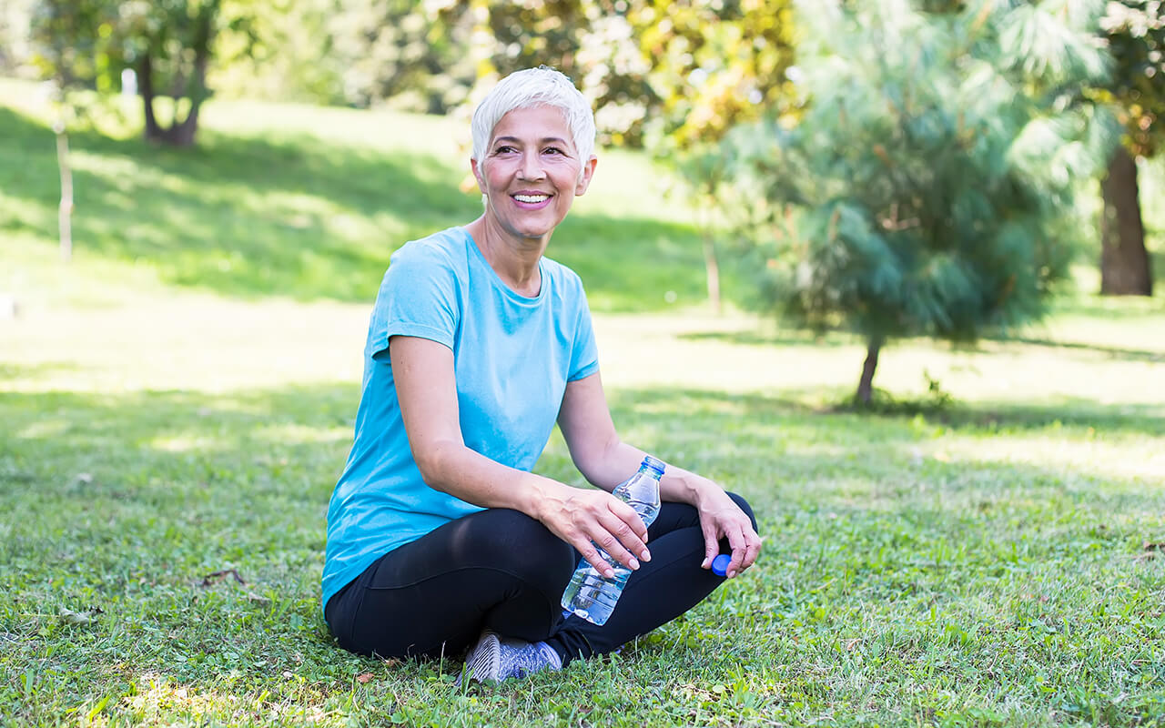 Woman sitting in grass holding a water bottle