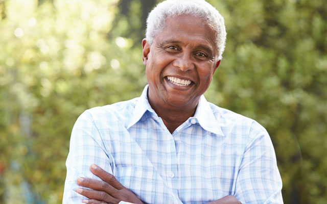 Man smiling with his arms crossed and wearing a blue and white plaid shirt 