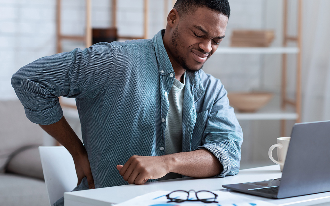 Man seated at desk wincing with back pain