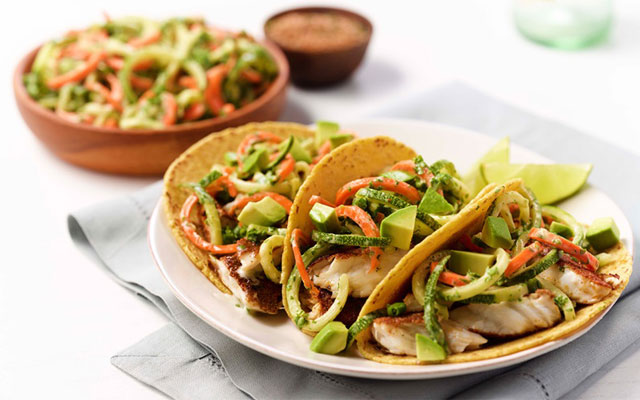 three fish tacos with carrots, zucchini, avocado, and lime