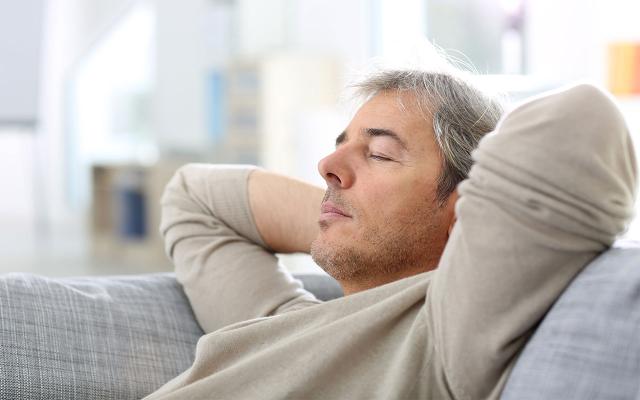 Man with eyes closed and hands behind head